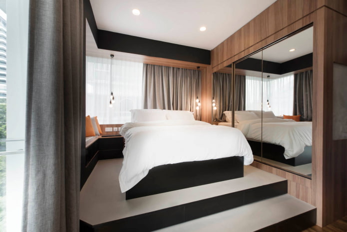 Cama sobre plataforma elevada com espelho lateral