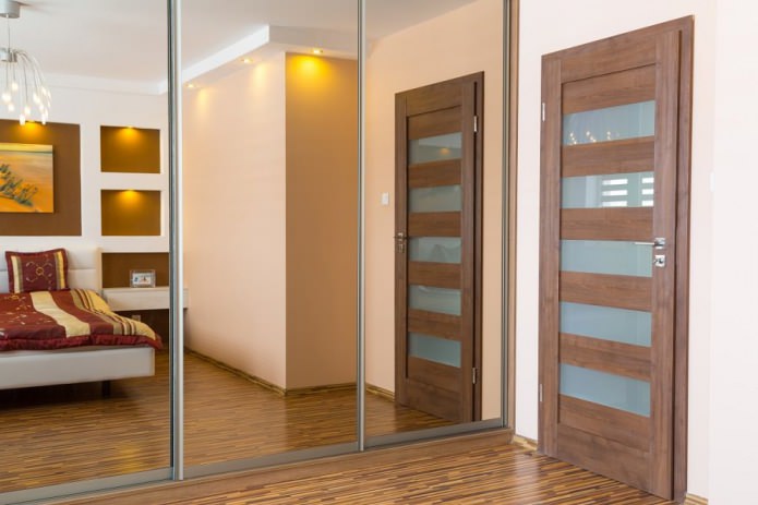 porta interna de madeira com inserções de vidro no interior do quarto