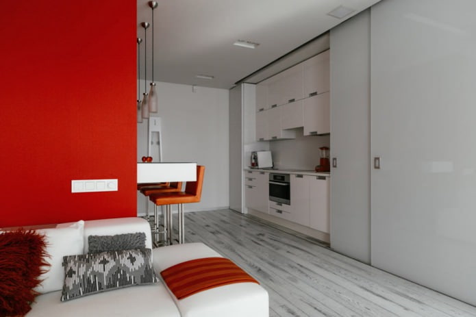 Balcão de bar no interior da cozinha-sala de estar em tons de branco e vermelho