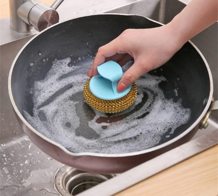 limpando uma frigideira com uma esponja dura