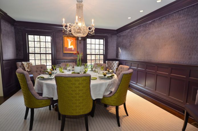 sala de jantar com papel de parede roxo escuro e cadeiras verdes e lilás