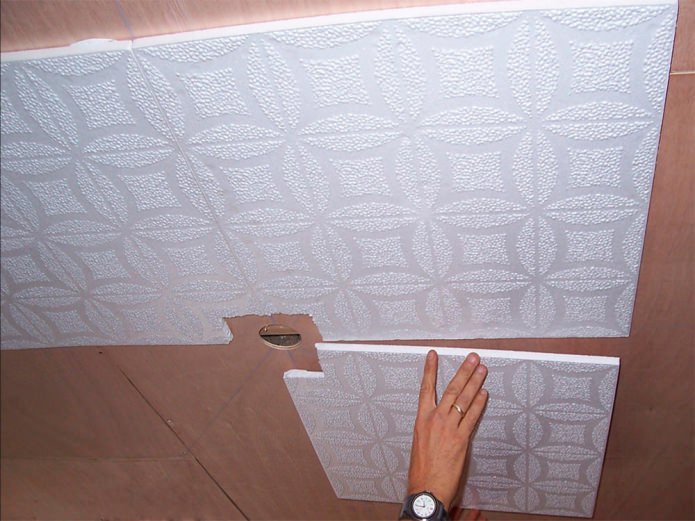 colando placas de poliestireno no teto 