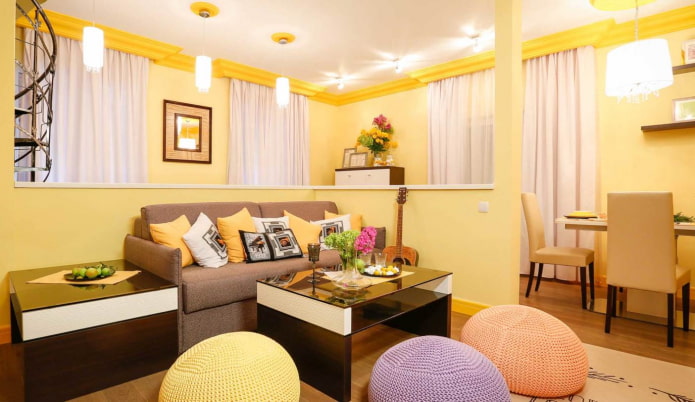 sala de estar amarelo claro com almofadas multicoloridas e pufes de tricô